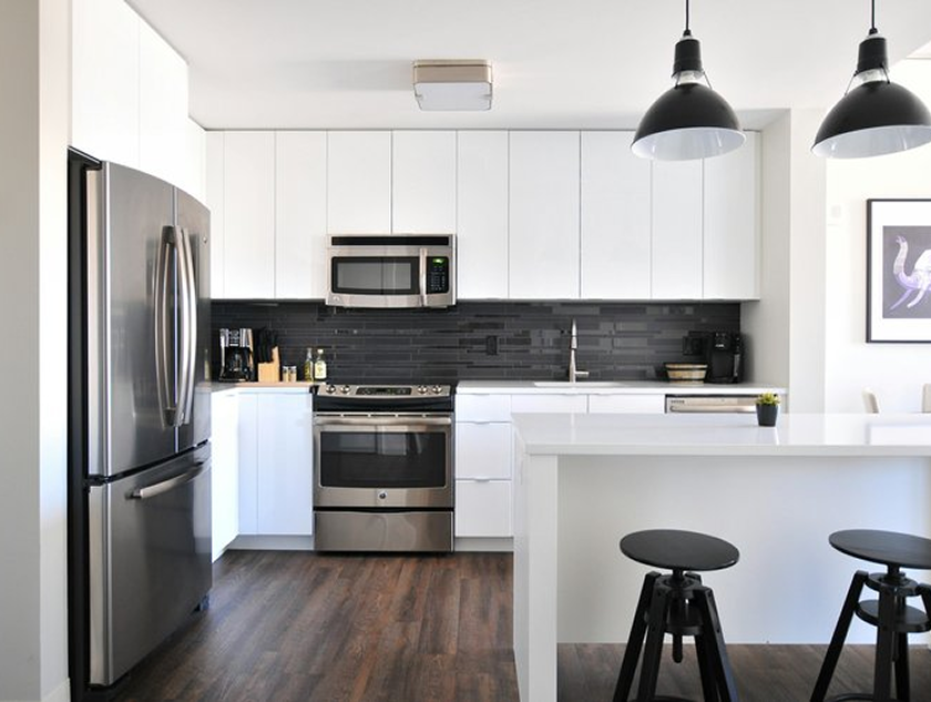 Kitchen with white shaker cabinets, a dark tile backsplash, and stainless steel appliances.