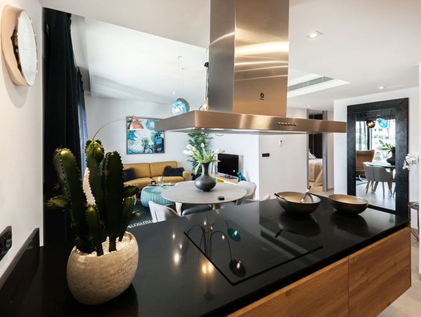 Kitchen island, open concept, with black built in cooktop stove and dark quartz countertops.