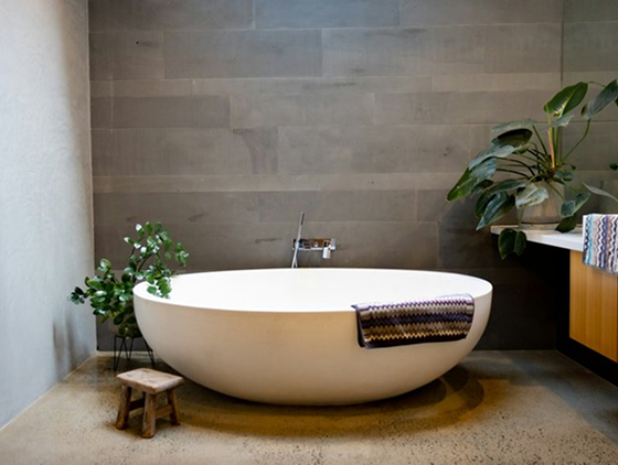 A freestanding tub in front of a large backsplash wall.