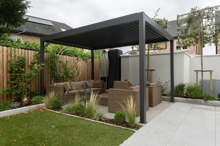 Modern freestanding patio cover with custom landscaping, fencing, and concrete.