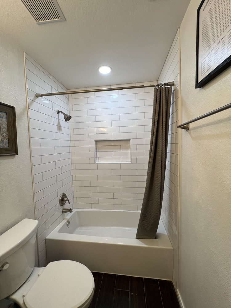 Remodeled tub and shower with 4x16 white subway tile. Including a shower niche and brushed nickel finishes.