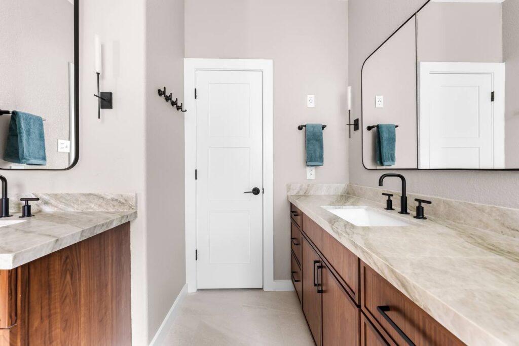 Annadale Dr. double vanity with walnut cabinets, light counters, black mirrors and sconces