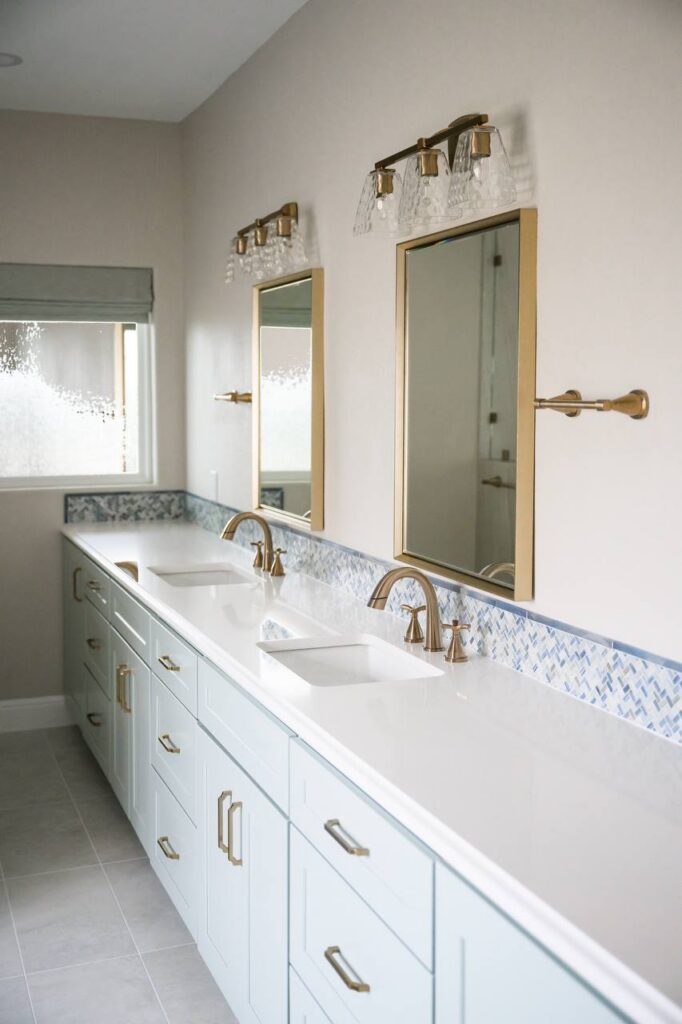 Spanish Oak double vanity with pale cabinetry, white countertop, brass fixtures
