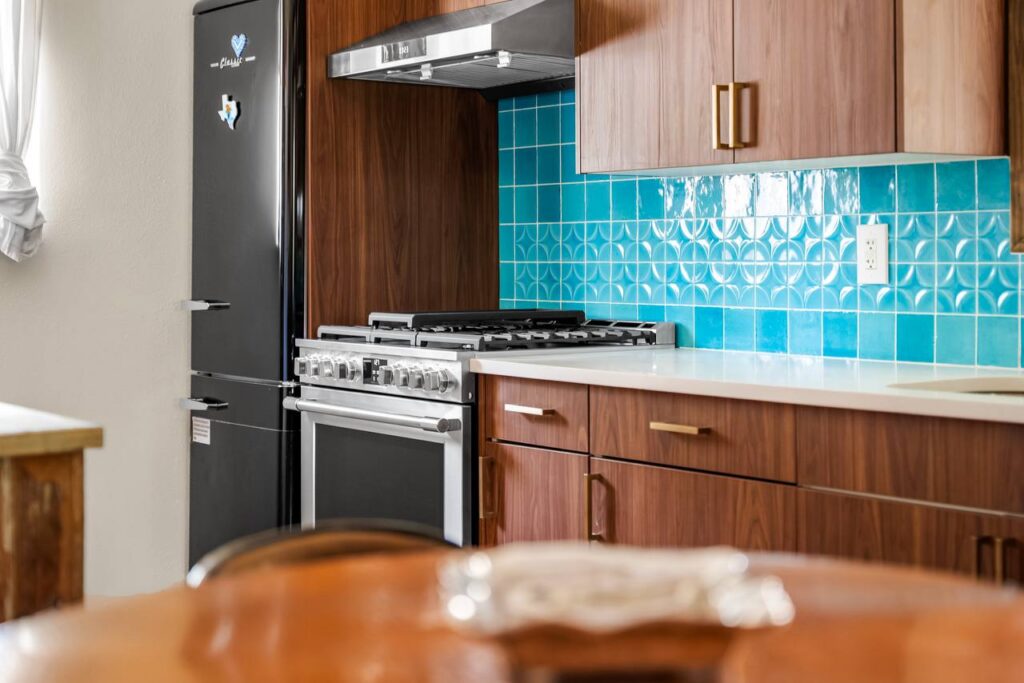 E 18th Street range and refrigerator wall with warm wood cabinets, bright tile