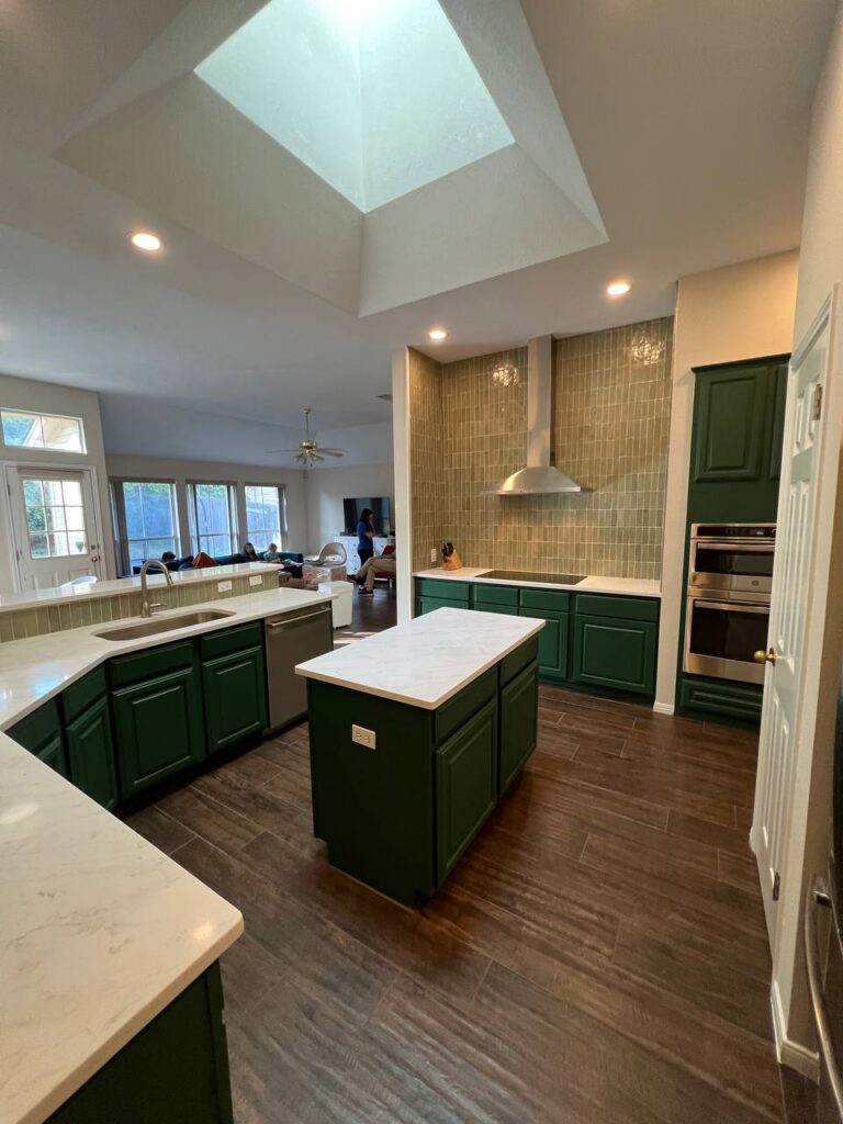 Dapplegrey kitchen with dark green island, white quartz counters, skylit open layout