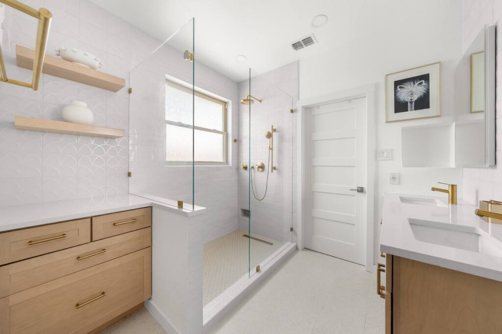 Lomita Verde bathroom with white tile, light wood vanity, and brass accents