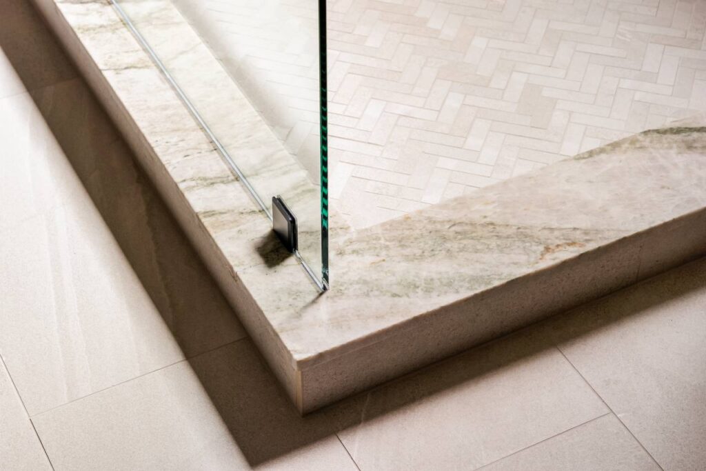 Annadale Dr. shower curb detail with stone threshold and herringbone floor tile