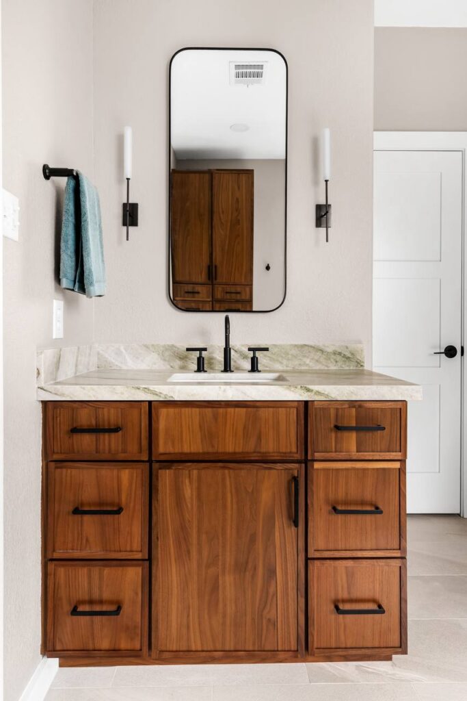 Annadale Dr. vanity with walnut cabinetry, light stone countertop, black faucet